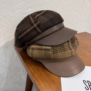 Detail of plaid newsboy hats with premium wool fabric and leather brim in warm retro tones