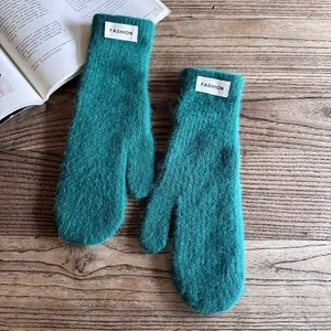 Close-up of plush turquoise faux rabbit fur mittens with fashion label on wood texture