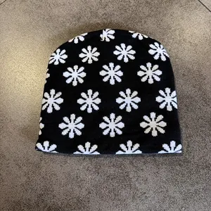 Macro view of black knit beanie featuring white floral patterns and textured embroidery