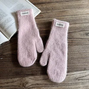 Detailed close-up of pink knit mittens with rib texture and FASHION patch detail