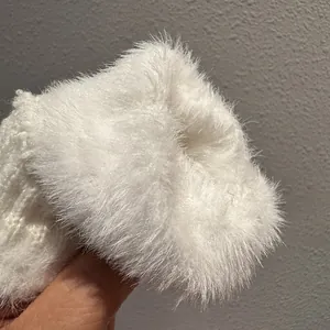 Dettaglio di guanti in peluche bianco che mostra la consistenza morbida e calda invernale
