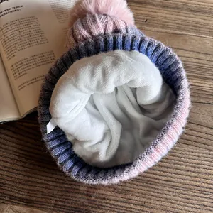 Détail du bonnet en tricot tie-dye avec doublure polaire blanche et pompon rose