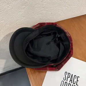 Detail of red plaid newsboy cap showing black inner lining and adjustable drawstring