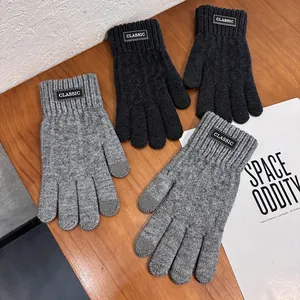Men's winter knit thermal gloves with touchscreen fingers and classic patch on wood background