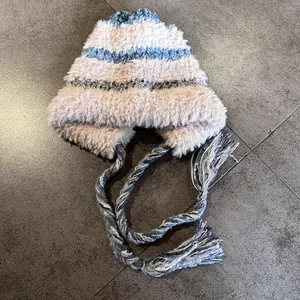 Detail of plush knitted trapper hat with blue stripes and decorative hanging tassels