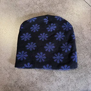 Close-up of soft black knitted beanie with vibrant blue floral patterns for winter