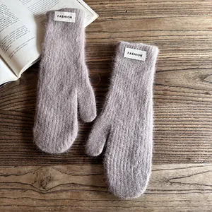 Detail of soft fuzzy knit mittens in dusty purple with white fashion label on wood