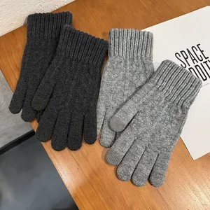 Detailed close-up of thick knitted winter gloves in black and grey on a wooden desk