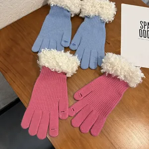Detail of knit gloves with plush trim and touchscreen finger openings on wood surface