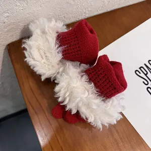 Red knit winter gloves with plush white trim on wooden surface for holiday warmth