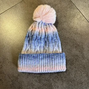 Détail de la maille torsadée et du pompon en fausse fourrure du bonnet dégradé