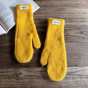 Macro view of bright yellow faux fur mittens with fashion label on wood background