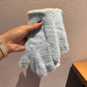Dettaglio di guanti in peluche azzurro con texture spessa e polsini colorati lavorati