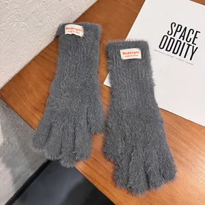 Detalle de mitones de felpa gris con textura suave de visón y etiqueta de marca cosida