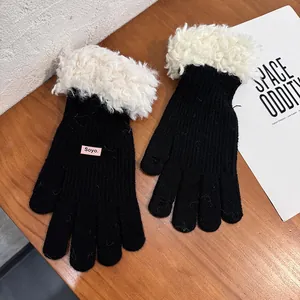 Detail of black knit gloves with white faux fur trim and small pink Soyo brand tag