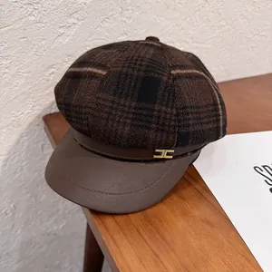 Detailed view of a brown plaid newsboy hat featuring leather brim and gold buckle