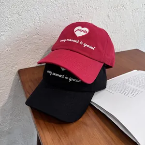 Classic cotton baseball caps in red and black with heart embroidery on wooden table