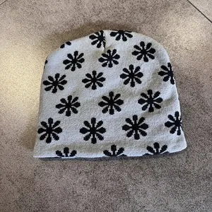 Detailed knit texture of light grey beanie with black floral jacquard pattern