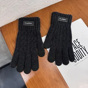 Detail of black knitted winter gloves with a white Classic label on a wooden background