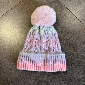 Détail du bonnet en tricot dégradé avec un pompon rose moelleux pour l'hiver