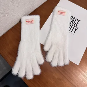 Detalle de guantes de felpa blancos con etiqueta de marca sobre fondo de madera