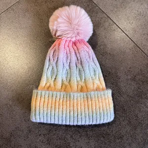 Gros plan sur la maille torsadée et le pompon rose du bonnet d'hiver dégradé