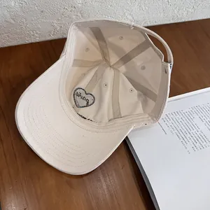 Detail view of cream cotton baseball cap interior showing sweatband and heart embroidery