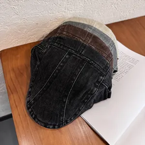 Vintage washed denim newsboy caps in black, coffee, grey, and beige on wooden table