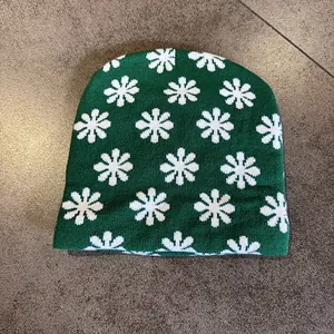 Close-up of green jacquard beanie showing white floral knit texture and warm material