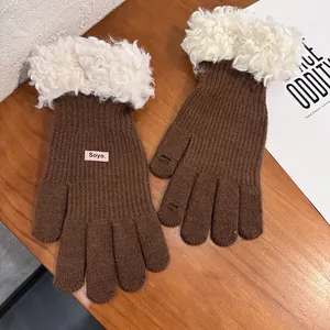 Detailed view of brown knit gloves with plush white cuffs and touch screen fingertips