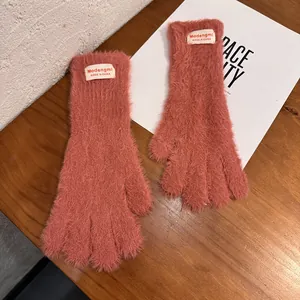 Detalle de guantes de invierno de felpa rosa coral con etiqueta de marca y textura suave