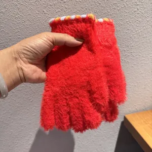 Dettaglio guanti in peluche rossi con consistenza soffice e polsini a righe per l'inverno