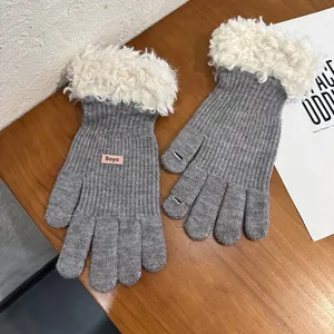 Detail of grey knitted touchscreen gloves with white plush cuffs and pink logo label