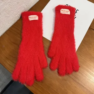 Primer plano de guantes rojos de punto de felpa con textura suave y etiqueta tejida