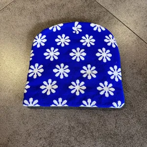 Detail of blue knitted beanie with white snowflake patterns and soft woven texture
