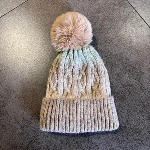 Gros plan d'un bonnet en maille épaisse avec dégradé de couleurs et pompon en fourrure