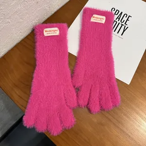 Detalle de guantes de punto de felpa rosa con textura suave y etiqueta de marca en puño