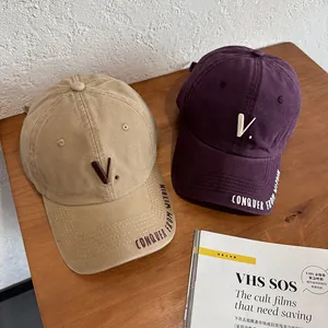 Detail of vintage washed cotton baseball caps with embroidered V letter and side slogan