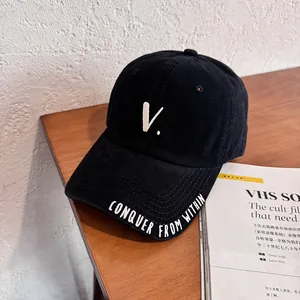 Close-up of black baseball cap with embroidered 'V' and 'CONQUER FROM WITHIN' slogan