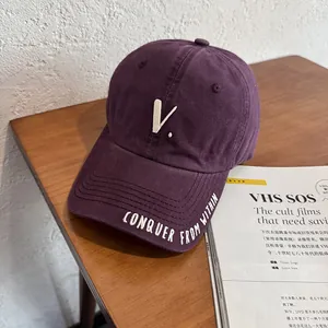 Detail of vintage purple baseball cap with white embroidered slogan on the brim edge