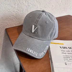 Detail shot of grey cotton baseball cap featuring embroidered V logo and slogan on visor