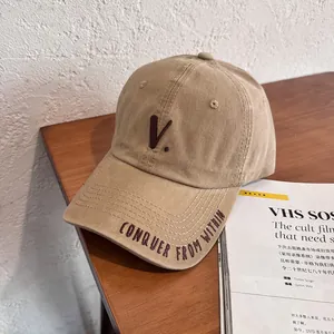 Detail view of khaki washed canvas baseball cap featuring letter V and Conquer From Within embroidery
