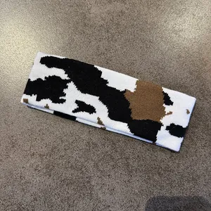 Close-up detail of knitted cow pattern headband showing soft elastic fabric texture