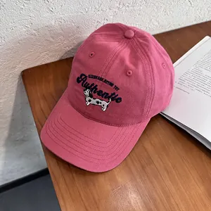 Dettaglio cappellino rosa con ricamo blu e motivo di un simpatico cucciolo di cane