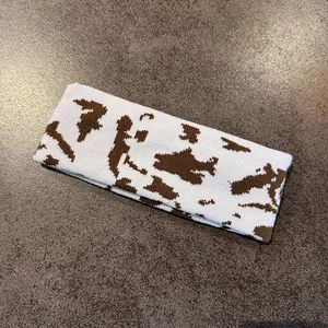 Detailed knit texture of white and brown cow print headband on stone background