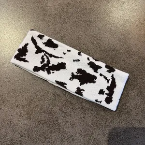 Close-up of knitted cow print headband featuring a soft black and white woven pattern
