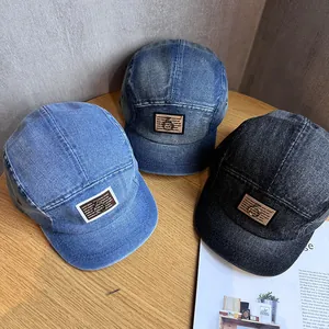 Three colors of denim baseball caps with metal rings on wooden table background