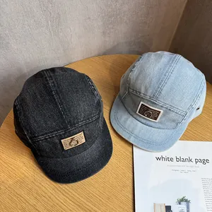 Close-up of washed denim baseball caps with metal ring labels on wood surface