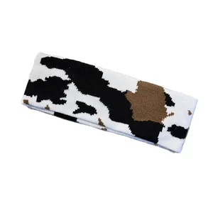 Knitted cow print sports headband for men and women in white with black and brown spots