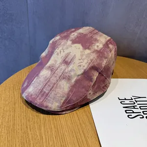 Detail of pink tie-dye vintage flat cap on wood table showing texture and visor